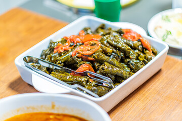 Turkish and Arabic Traditional Ramadan Food Stuffed grape leaves with rice and meat, Sarma with tomato slices on a white plate. Sarma is a dish of grapes. Copy space for text area. High quality photo