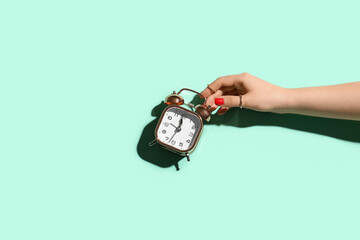 Woman with beautiful manicure holding alarm clock on color background