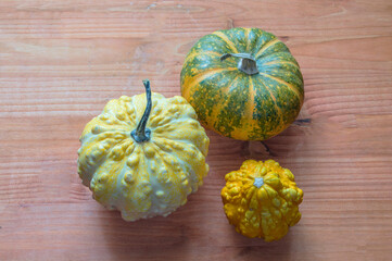 three small yellow pumpkins on wooden background