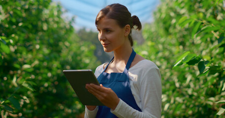 Fototapeta premium Woman farmer collecting data with modern device in green plantation smiling