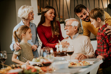Family celebrating grandfather birthday with cake and candles at home