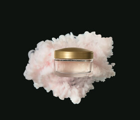 Jar of cosmetic product in pink smoke on black background
