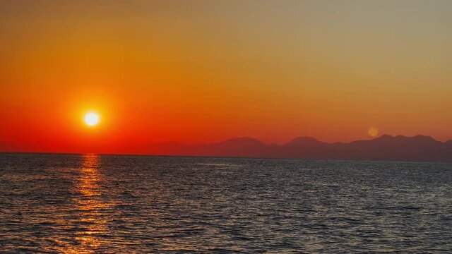 Picturesque sunset against the backdrop of mountains from a yacht in motion