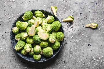 Bowl with fresh raw Brussels cabbage on grey background