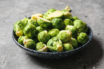 Bowl with raw ripe Brussels cabbage on grey background