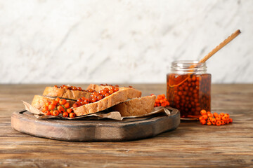 Board with tasty sandwiches and rowan jam on wooden table