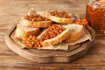 Board with tasty sandwiches and rowan jam on wooden background, closeup