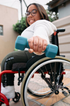 Woman in a wheelchair lifting weight at home