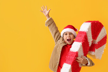 Cute little boy with candy cane pinata on color background