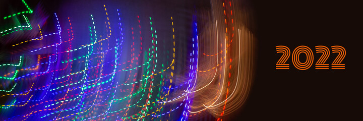 Abstract background of Christmas lights with long exposure. Colorful 2022 number on black background