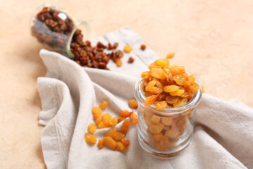 Glass jar with tasty raisins on color background, closeup