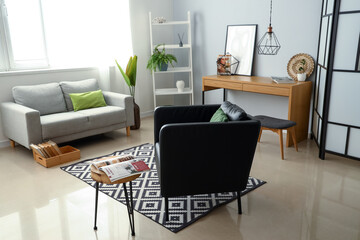 Black armchair and table with magazine in interior of living room