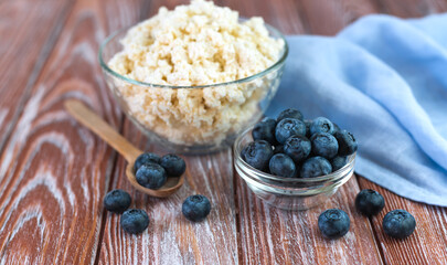 Fresh blueberries and cottage cheese on the wooden background. Selective focus. Healthy breakfast in the morning. Close-up.