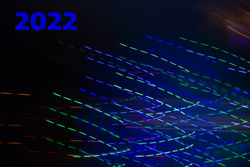 Abstract background of Christmas lights with long exposure. Colorful 2022 number on black background