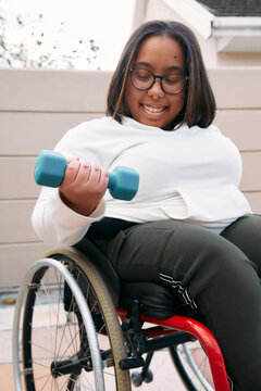 Woman in a wheelchair lifting weight at home