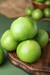 Board with fresh tomatoes on green wooden background