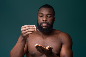 African bearded man with pimples  applying oil on his skin