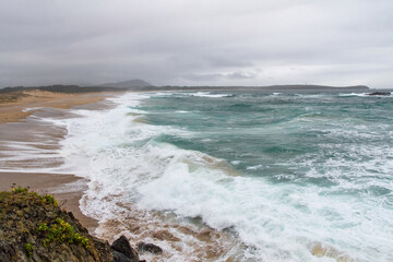 General view of the Valdoviño beach with the live sea a day of storm and lighthouse in the background 