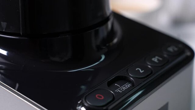 Woman presses button Ice Crush on blender and ice begins to crush. Then crushing is done, woman turns off the blender. Close-up. High quality 4k footage