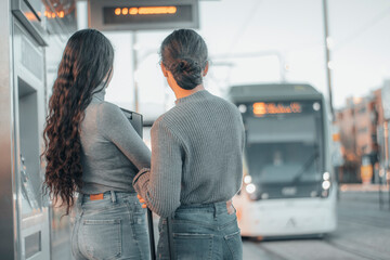 Mujeres en equipo de negocios observando la llegada del metro en la estación de trenes en frente de los railes para transportarse junto con su boleto y equipaje viajando para llegar a su trabajo