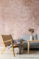 Comfortable armchair, sofa and table with vase near color wall