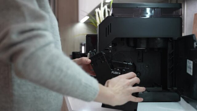 Woman has a coffee machine in the kitchen and she wants to service it. Woman opens a coffee machine and remove a brewing unit to clean it. High quality 4k footage