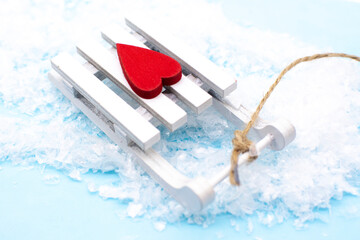 Happy New Year. White sled with a red heart and snow on a blue background. New year and merry Christmas concept.