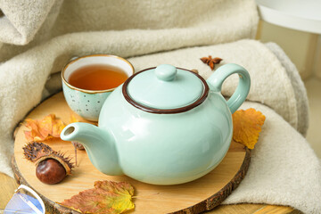 Tea pot and autumn leaves on table in room