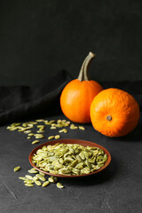 Plate of pumpkin seeds on black background