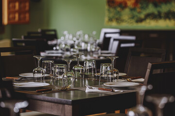 Laid table in the restaurant. There are empty wine glasses on the table.