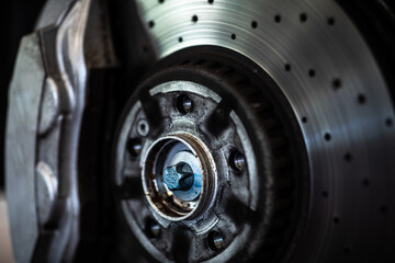 Car in a garage for maintenance, oil, tyre change (shallow DOF; color toned image) - disc brakes detail
