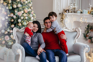 Happy family, in the New Year's interior near the Christmas tree.