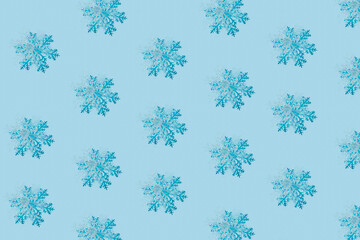 Winter Christmas pattern with snowflakes on pastel blue background. Minimal Xmas eve or Happy New Year celebration concept. Elegant winter holidays greeting card. Flat lay, top view.