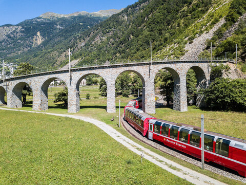 Brusio, Switzerland: 26 August 2018 - Bernina Express is going through the famous circular viaduct in Swiss Alps mountain, Canton Grisons, This spiral viadukt is a unesco heritage. opened in 1908.