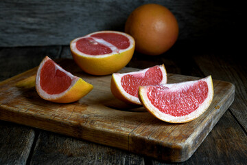 Sliced grapefruit with a knife on a cutting board in the kitchen on a wooden table.