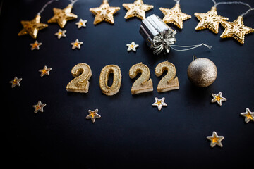 Happy New Year 2022. Holiday background with golden Christmas decorations . 2022 numbers with gold jewelry balls and garland in form of stars