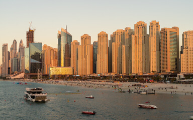 Fototapeta na wymiar Dubai Marina Skyscrapers at Sunset. The golden hue of sunset bathes the impressive skyscrapers of Dubai Marina, showcasing the architectural prowess of the city