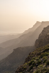Fototapeta na wymiar Jabal Samhan's Mountain Silhouettes. Gentle hues bathe the rolling silhouettes of Jabal Samhan's mountain range, offering a calm and layered perspective of Oman's diverse topography.
