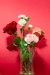 Big red rose with white carnations bouquet close up. Red background interior. Florist shop display with copy space. 