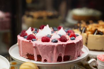 Chocolate biscuit and berry mousse cheesecake. Round pie with pink icing. Raspberry with blueberry and meringue décor.
