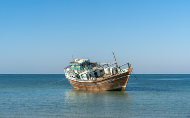 Obraz premium Abandoned Wooden Dhow on Still Water, Oman