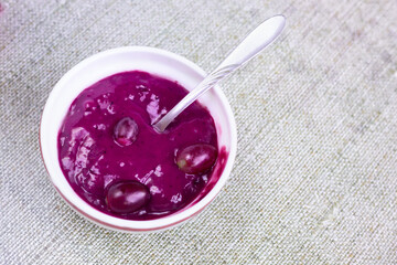 Blue violet fruit sweet porridge. Purple creamy smoothie with fruits close up.