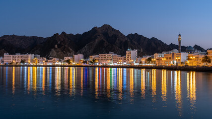 View of the harbour of Muscat with colourful reflecting city lights at night