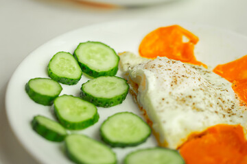 Soft focus, breakfast plate. Selective focus. Sliced cucumber, fried scrambled eggs close up.	