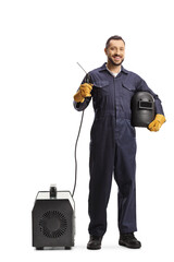 Full length portrait of a welder in a uniform holding a welding generator and  face shield