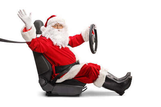 Santa Claus in a car seat holding a steering wheel and waving at camera