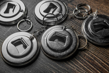Metal openers for glass bottles lie on a wooden table.