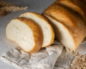 Fresh homemade white bread with slices isolated on white linen towel.White bread with wheat spikelet