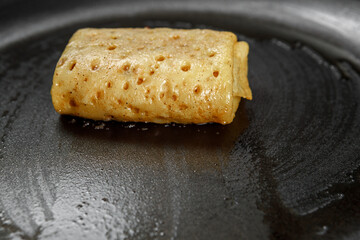 The stuffed pancake lies in a frying pan, with a non-stick coating, greased with oil.