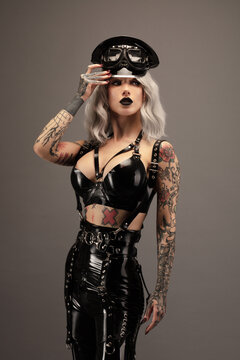 Attractive tattooed young woman wearing latex lingerie and cap